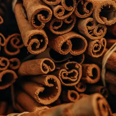 A pile of brown, rolled cinnamon sticks with a natural, textured bark surface.